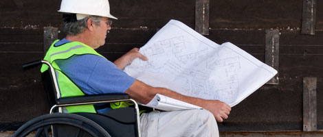 Man in wheelchair looking at blueprints.