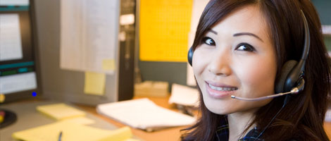 A woman working at her desk smiling with phone headset.